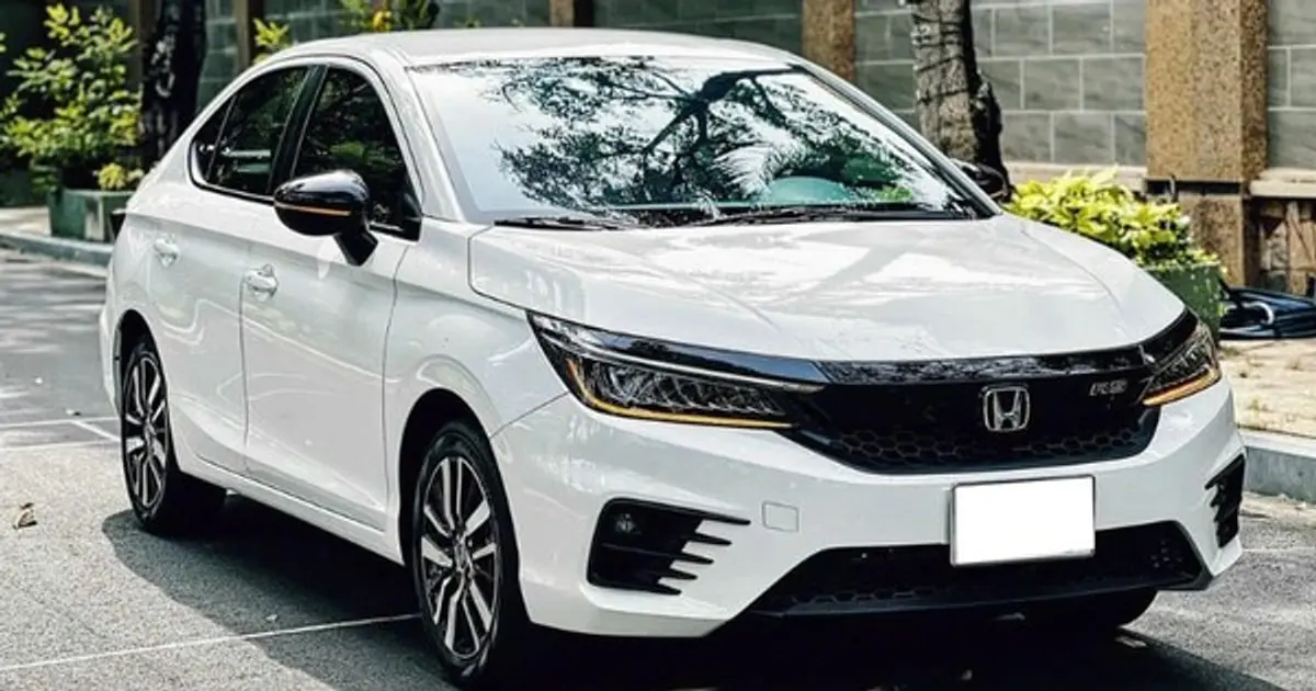 Một chiếc Honda City đang di chuyển trên đường phố, phía sau là một gia đình nhỏ đang cười vui vẻ.