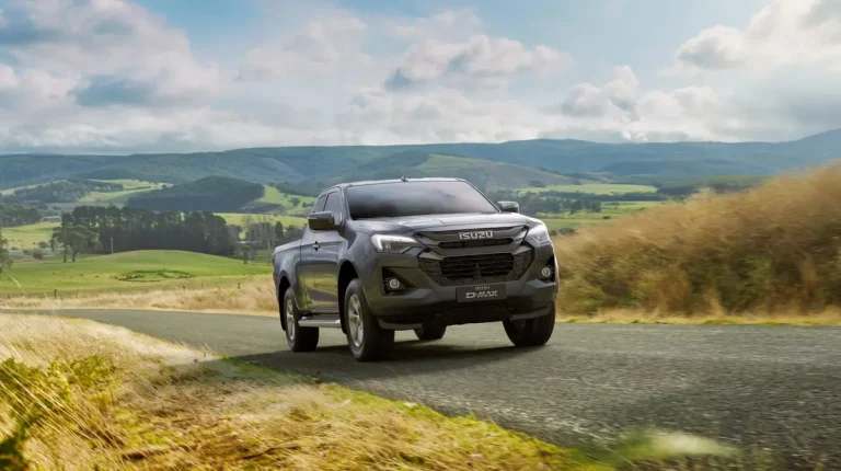 Xe bán tải Isuzu D-Max màu trắng đang di chuyển trên đường đất, thể hiện khả năng vượt địa hình.