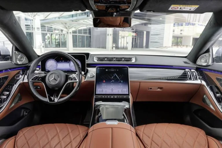Nội thất ghế sau Mercedes-Maybach S500 màu kem với màn hình giải trí, bàn gấp và tủ lạnh mini.