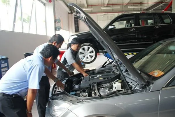 Một kỹ thuật viên đang kiểm tra động cơ của chiếc Mercedes C250 đã qua sử dụng.