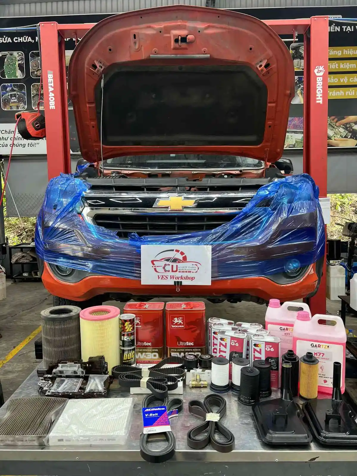 Hình ảnh thợ kỹ thuật đang kiểm tra động cơ hoặc các bộ phận khác của xe Chevrolet tại một garage, minh họa cho việc bảo dưỡng xe định kỳ và chuyên nghiệp.