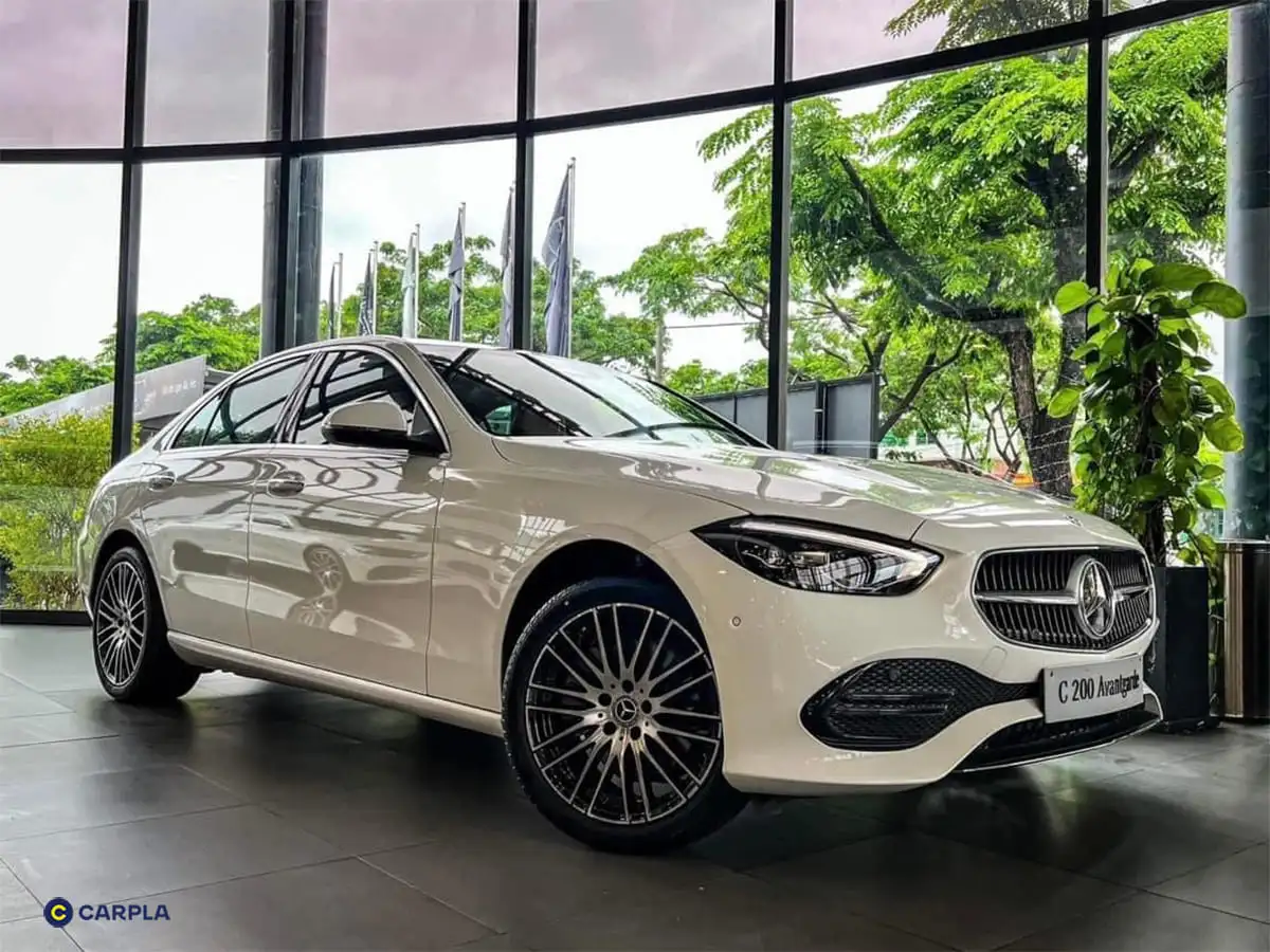 Hình ảnh Mercedes C200 thế hệ W206 màu trắng đang di chuyển trên đường, thể hiện vẻ ngoài sang trọng và thể thao của dòng xe.